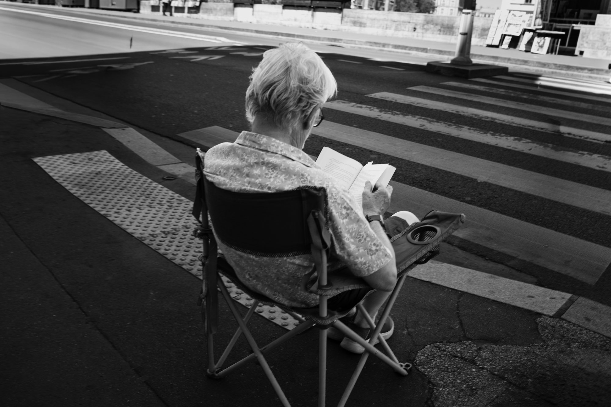 Elle lit, installée face au passage piéton.